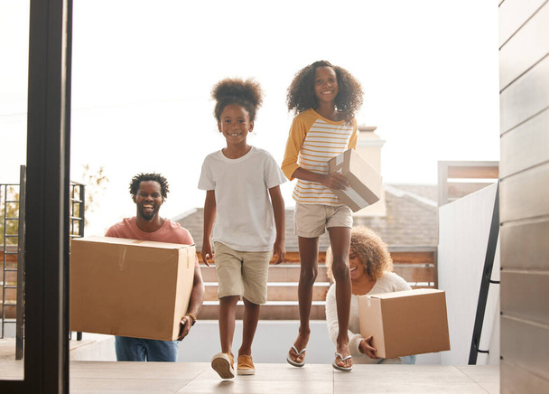 Happy, family and walking with boxes in new home for real estate, walking or together for future. Group, people and house with investment or growth for children, welcome or property with mortgage. - Photo, Image