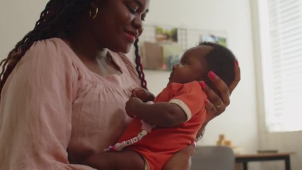 Tilt up shot van zwarte vrouw spelen met pasgeboren dochtertje en kussen in het voorhoofd - Video