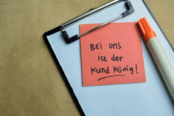 Concepto de Bei Uns Ist der Kund konig escribir en notas adhesivas aisladas en la mesa de madera. - Foto, imagen
