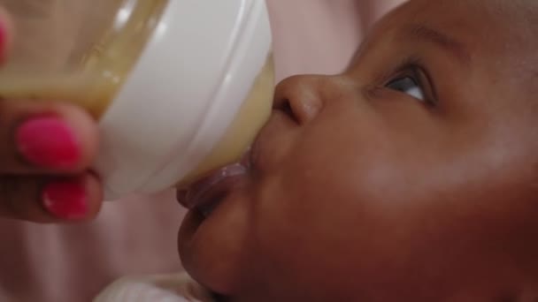 Side view close up of cute newborn baby sucking from bottle with lactose formula in mothers hands - Footage, Video