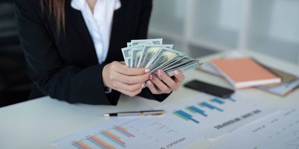 Businesswoman or financial bookkeeper holding bundle of money dollar for payment salary and income. entrepreneur counting money cash count salary profit finance at office. - Photo, Image