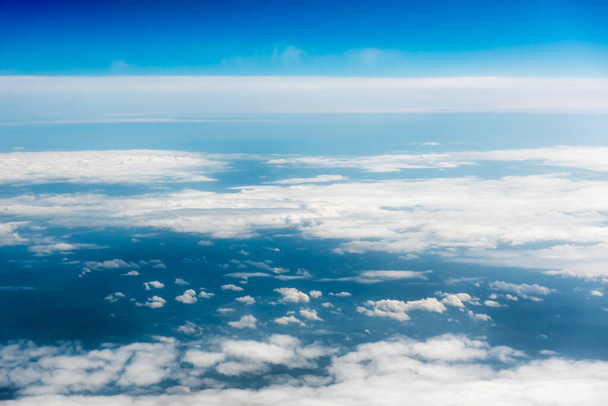 Witte cumulus wolken op heldere blauwe lucht achtergrond close-up, bewolkte luchten achtergrond, pluizige wolk textuur, prachtige zonnige wolkenlandschap hemel. Wit wolkenzicht vanuit vliegtuig - Foto, afbeelding