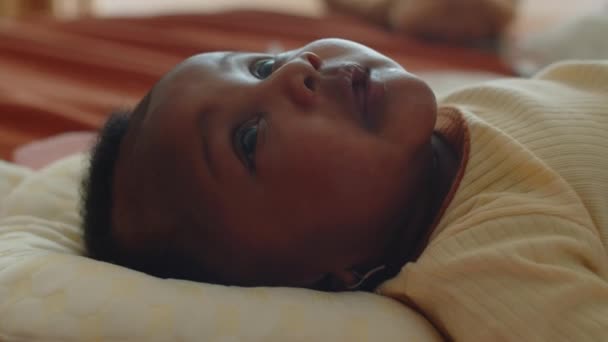 Side close-up uitzicht van zwart pasgeboren baby kijken naar alles rond terwijl liggend in bed - Video