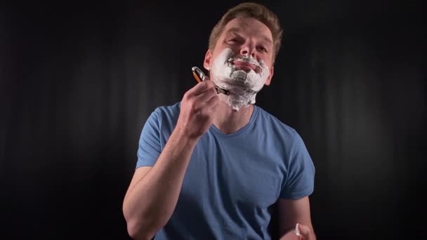 Modern masculine self-care. A stylish young man engages in grooming routine on a minimal black backdrop indoors. This intimate portrayal celebrates the confidence of prioritizing personal upkeep - Footage, Video