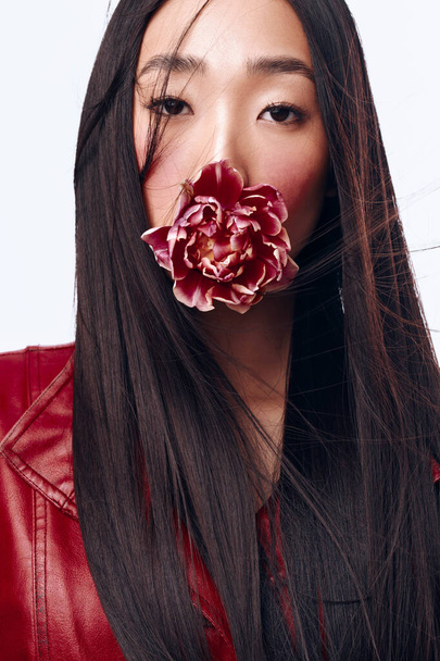 Hermosa mujer en chaqueta roja sosteniendo la flor, su pelo largo soplando en el viento - Foto, imagen