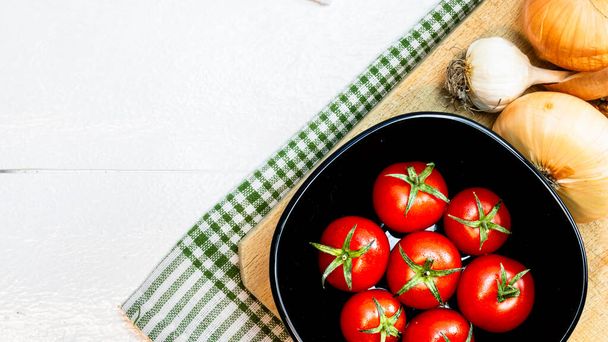 Vista dall'alto di cipolle, aglio e pomodorini freschi maturi su un tavolo di legno bianco rustico. Ingredienti e concetto di cibo
 - Foto, immagini