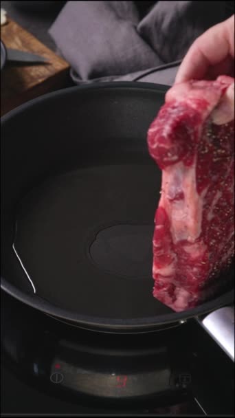 surowe mięso ze steków jest umieszczane na patelni w podgrzewanym oleju, proces gotowania steku, zbliżenie żywności - Materiał filmowy, wideo