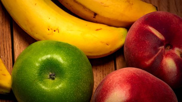 Jablko, broskev a banány na dřevěné desce. Složení zdravého ovoce. - Fotografie, Obrázek