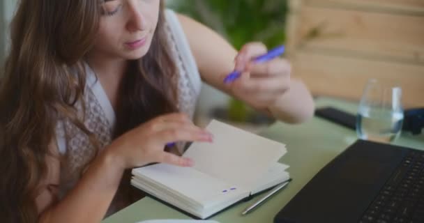 Close-up van een gefocuste vrouwelijke student die notities schrijft - Video