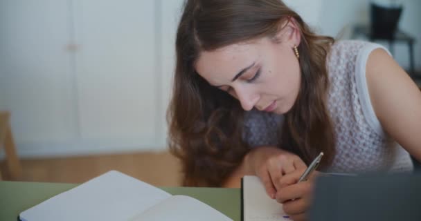 Mujer escribe diligentemente en cuaderno, estudiando y haciendo la tarea - Metraje, vídeo