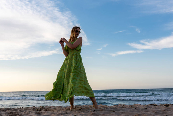 Щаслива жінка, що гуляє на пляжі на заході сонця. Красива жінка щаслива розслабтеся, гуляючи на пляжі біля моря, коли захід сонця ввечері. - Фото, зображення