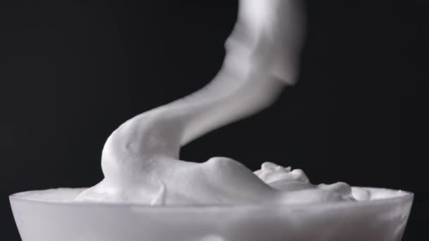 A séf összekeveri a tejszínhabos tojásfehérjét cukorral és kanállal keveri, desszertkészítési folyamat, közelkép az ételről - Felvétel, videó