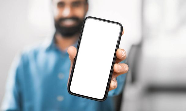Unrecognizable man holding a modern cell phone device in his hand, looking at the screen. The background is indiscernible, focusing solely on the man and the phone. - Photo, Image