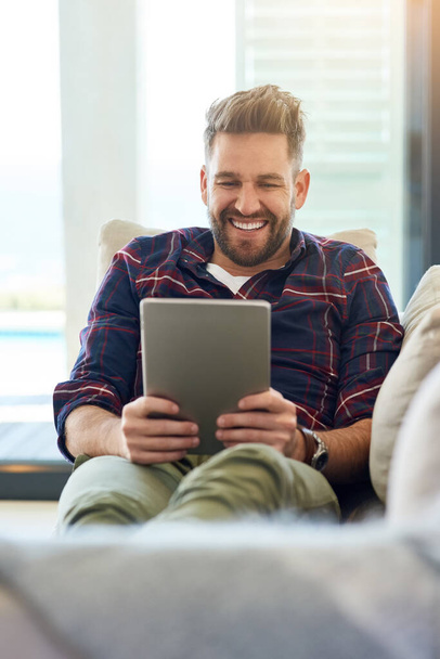 Tablet, search and happy man laughing on sofa for social media, ebook or streaming video at home. Digital, funny and living room with comic, movie or show, comedy or relax with app gif communication. - Photo, Image