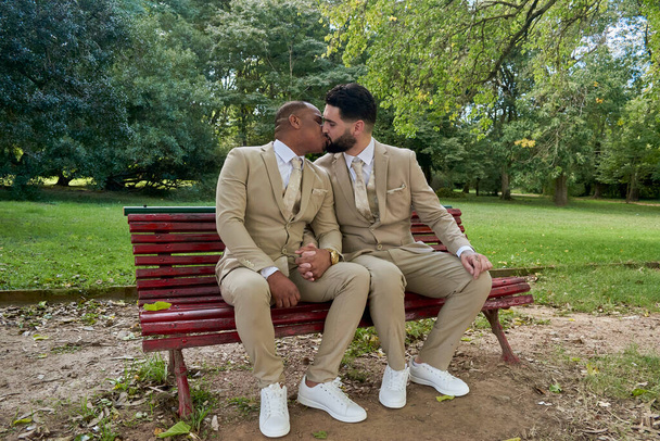 Δυο νιόπαντροι άντρες φιλιούνται για να γιορτάσουν το γάμο τους. Έννοια της γκέι υπερηφάνειας και της σεξουαλικής ποικιλομορφίας - Φωτογραφία, εικόνα