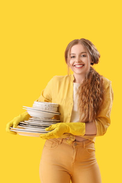 Junge Frau mit schmutzigem Geschirr auf gelbem Hintergrund - Foto, Bild