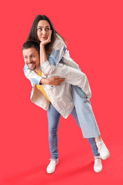 Glückliches junges Paar auf rotem Hintergrund - Foto, Bild