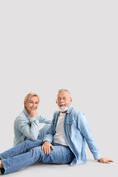 Ältere Paare in Jeanskleidung sitzen auf hellem Hintergrund - Foto, Bild