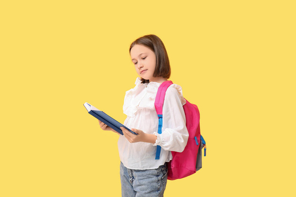 Kis iskoláslány olvasás könyv sárga háttér - Fotó, kép