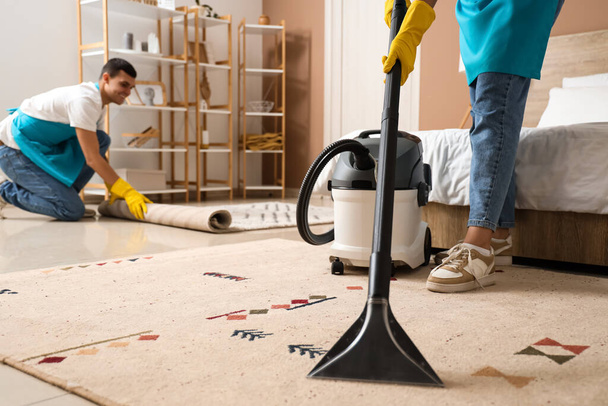 Female janitor cleaning carpet in bedroom - Photo, Image