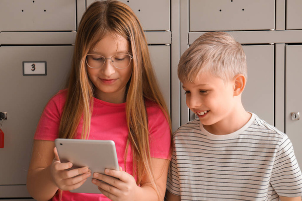 Pupilas usando tableta cerca de casillero en la escuela - Foto, Imagen