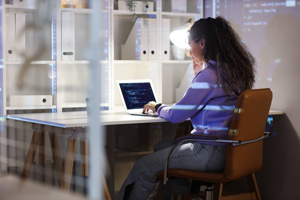 Женщина-афро-американский программист, работающая с ноутбуком в офисе ночью - Фото, изображение