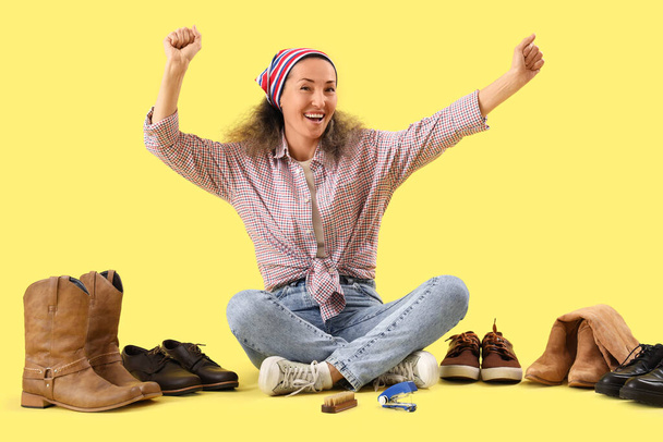 Joyeux cordonnier féminin avec des chaussures assises sur fond jaune - Photo, image