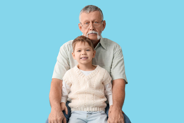 Grootvader met zijn vrolijke schattige kleinzoon op blauwe achtergrond - Foto, afbeelding