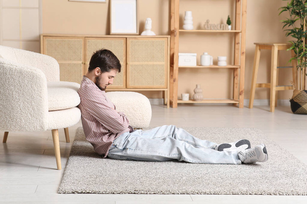 Unavený mladý muž spí na podlaze doma - Fotografie, Obrázek
