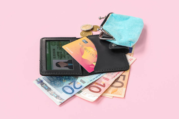 Samenstelling met zwarte houder, creditcards, rijbewijs, portemonnee en geld op roze achtergrond, close-up - Foto, afbeelding
