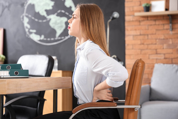 Joven mujer de negocios que sufre de dolor de espalda en la silla en la oficina - Foto, imagen