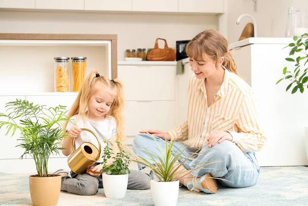 Nounou avec petite fille arrosage plantes dans la cuisine - Photo, image