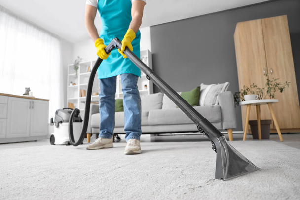 Чоловічий прибиральник чистить килим у кімнаті - Фото, зображення