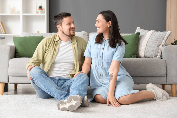 Junges Paar sitzt zu Hause auf weichem Teppich - Foto, Bild