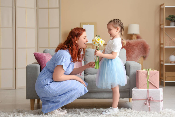 Mała dziewczynka daje matce kwiaty w domu. Dzień Matki - Zdjęcie, obraz