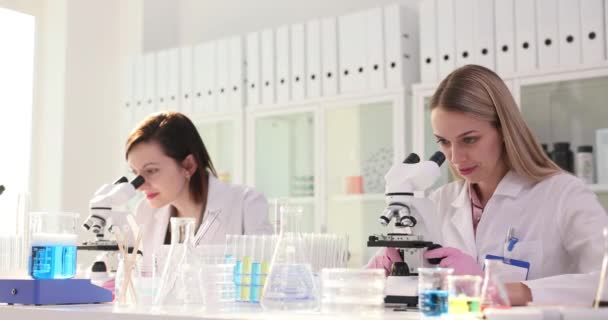 Kobiety-naukowcy badają próbki za pomocą mikroskopów w laboratorium. Koleżanki i koledzy wyrażają zadowolenie z wyników dających przybicie piątki w zwolnionym tempie - Materiał filmowy, wideo