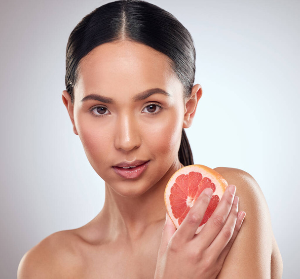 Krása, strava a grapefruit s portrétem ženy ve studiu na bílém pozadí pro wellness. Estetika, ovoce a výživa s tváří seriózního modelu v lázních pro kosmetiku, dermatologii nebo péči o pleť. - Fotografie, Obrázek
