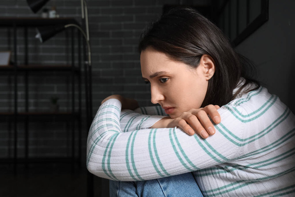 Депрессивная молодая женщина в темной комнате, крупный план - Фото, изображение