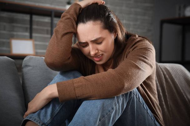 Депрессивная молодая женщина на диване дома, крупным планом
 - Фото, изображение