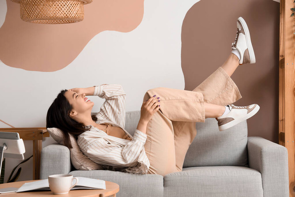 Giovane donna sdraiata sul divano grigio a casa - Foto, immagini