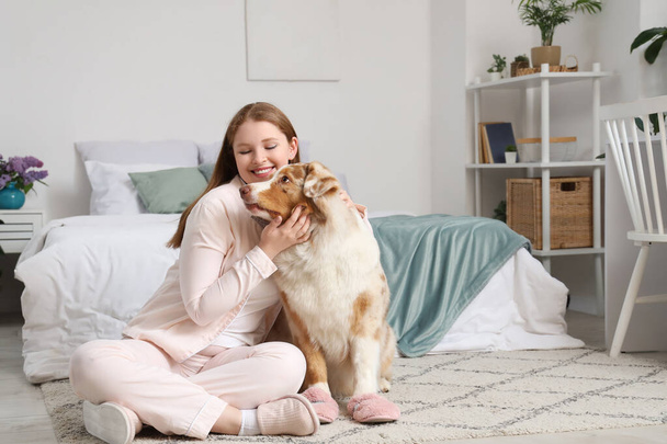Giovane donna e simpatico cane pastore australiano con pantofole a casa - Foto, immagini