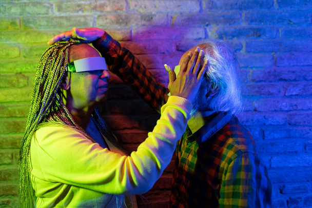 Két VR szemüveges végzős, akik mélyen részt vesznek egy színes, interaktív élményben.. - Fotó, kép