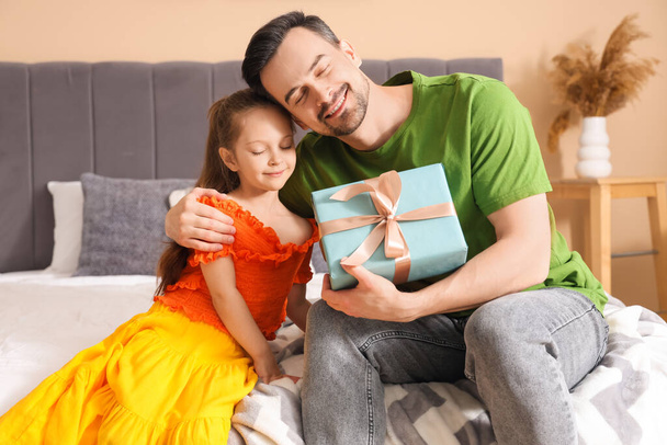 Hijita dándole regalo a padre en el dormitorio. Celebración del Día del Padre - Foto, Imagen