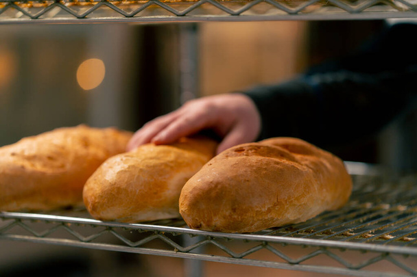Крупный план свежеиспеченного теплого хлеба на железной стойке на профессиональной кухне - Фото, изображение