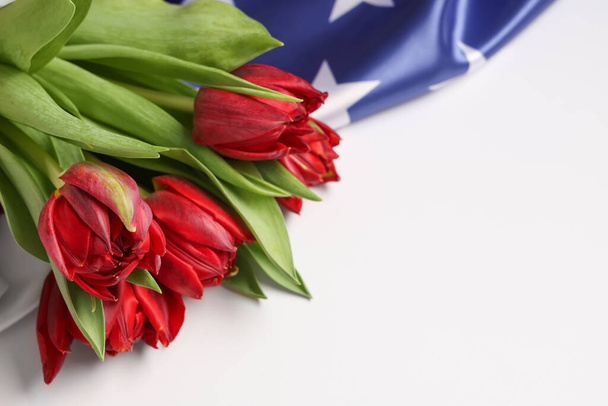Красивые цветы тюльпана и флаг США на светлом фоне, крупным планом. Праздник памяти - Фото, изображение