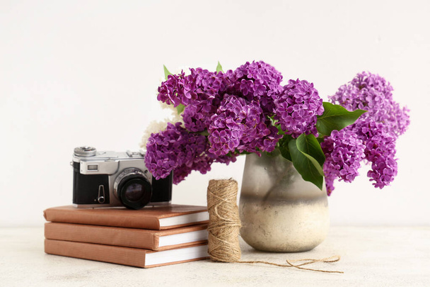 Váza s kvetoucími šeříkové květy, knihy a fotoaparát na bílém pozadí - Fotografie, Obrázek