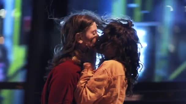 LGBT lesbiana beso en la noche en la ciudad con el tráfico de autobús de movimiento pasando en segundo plano - Metraje, vídeo
