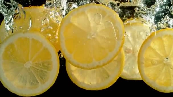 Super Slow Motion Shot de rodajas de limón fresco cayendo y fluyendo en el agua sobre fondo negro a 1000 fps. Filmado con cámara de cine de alta velocidad en resolución 4K. - Imágenes, Vídeo