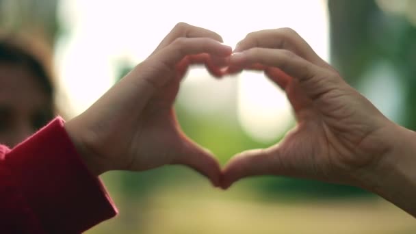 Ręce robią symbol kształtu serca i trzymają się za ręce. - Materiał filmowy, wideo