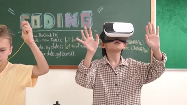 VR kulaklık takan enerjik bir çocuk sınıfta sanal dünyaya giriyor. Öğrenci programlama sistemi, çocuk elektronik panoyu tamir ederken yapay zeka ile mühendislik komut yazılımı oluşturdu. Pedagoji. - Video, Çekim